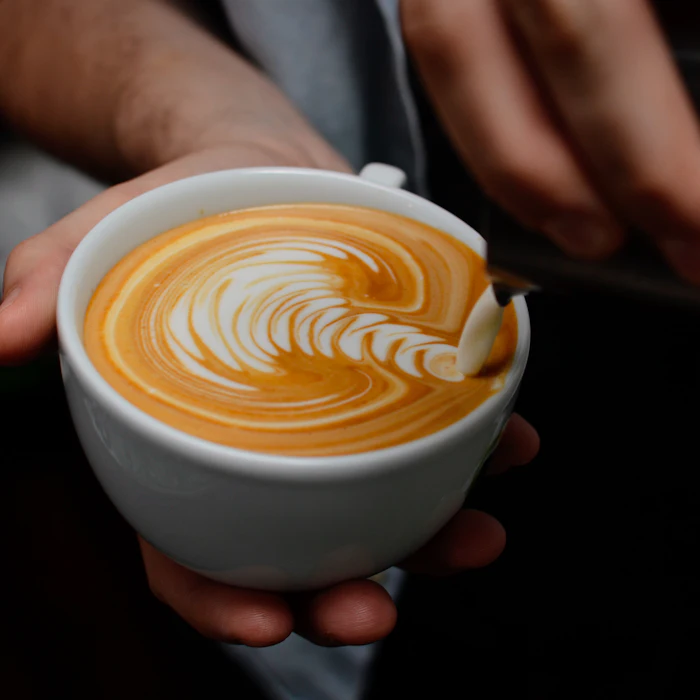 Barista sirviendo un café con latte art