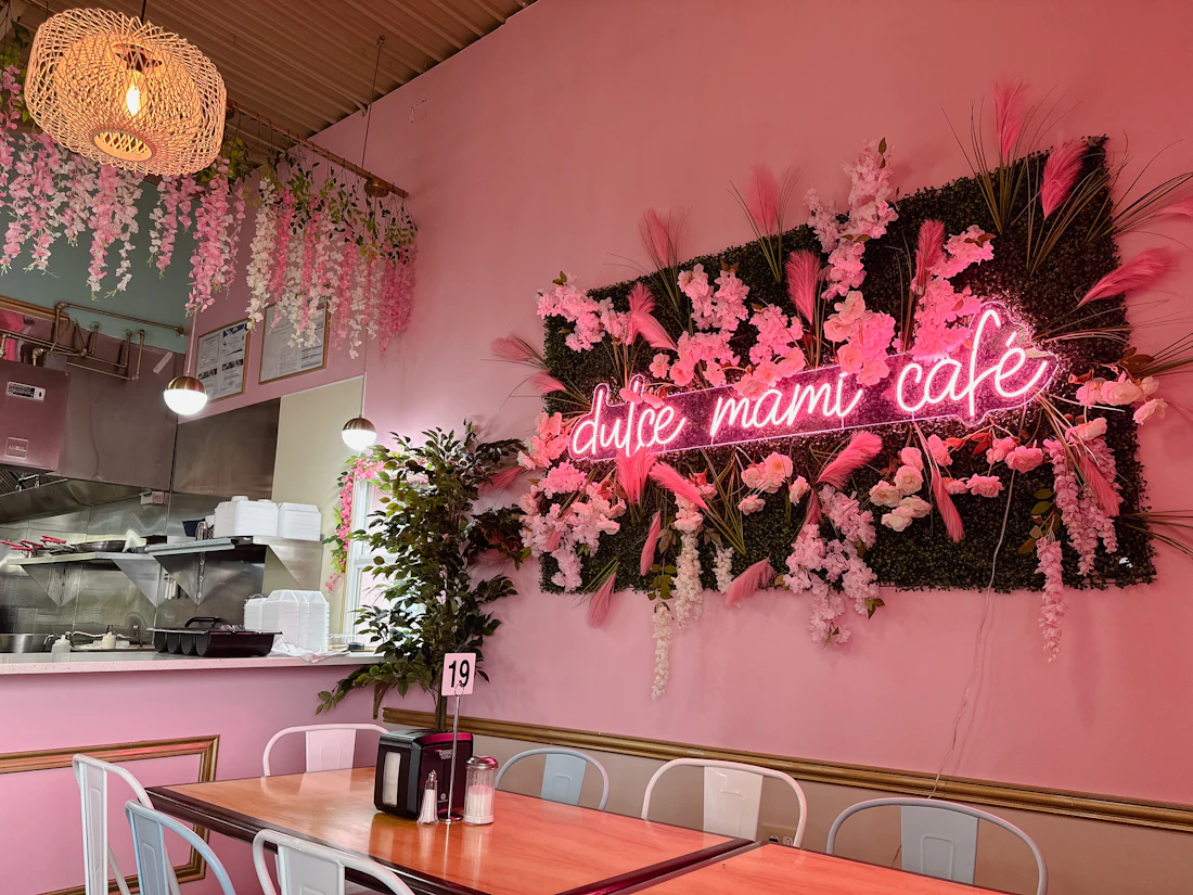 Interior de cafetería rosa con neón y flores